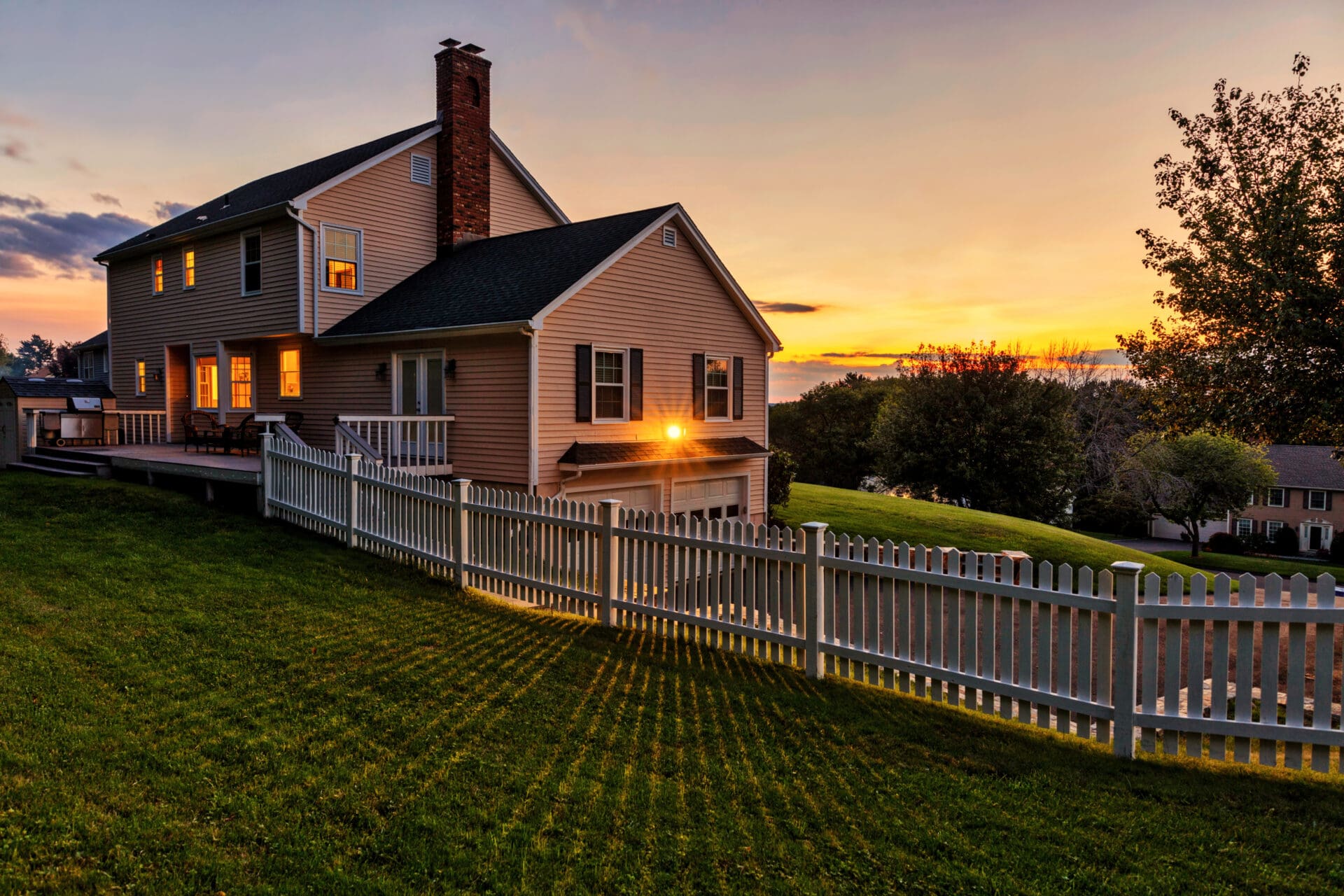 Sunset view of suburban home with fence.