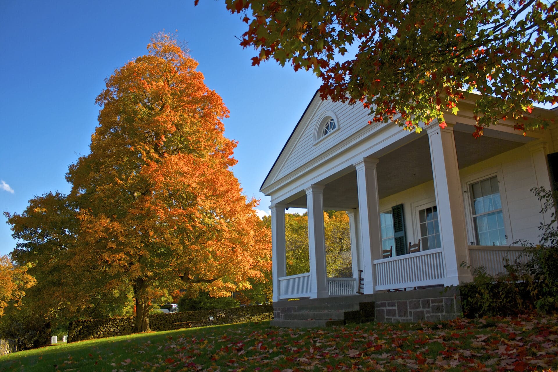 Autumn leaves frame a white porch.